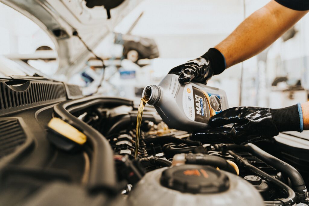 A professional technician pouring fresh motor oil into a vehicle engine during an oil change service at a Redmond Washington auto repair shop