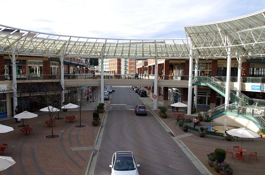 Elevated view of Redmond Town Center's outdoor retail plaza in Redmond, Washington, showing storefronts, a paved street, and outdoor cafe seating