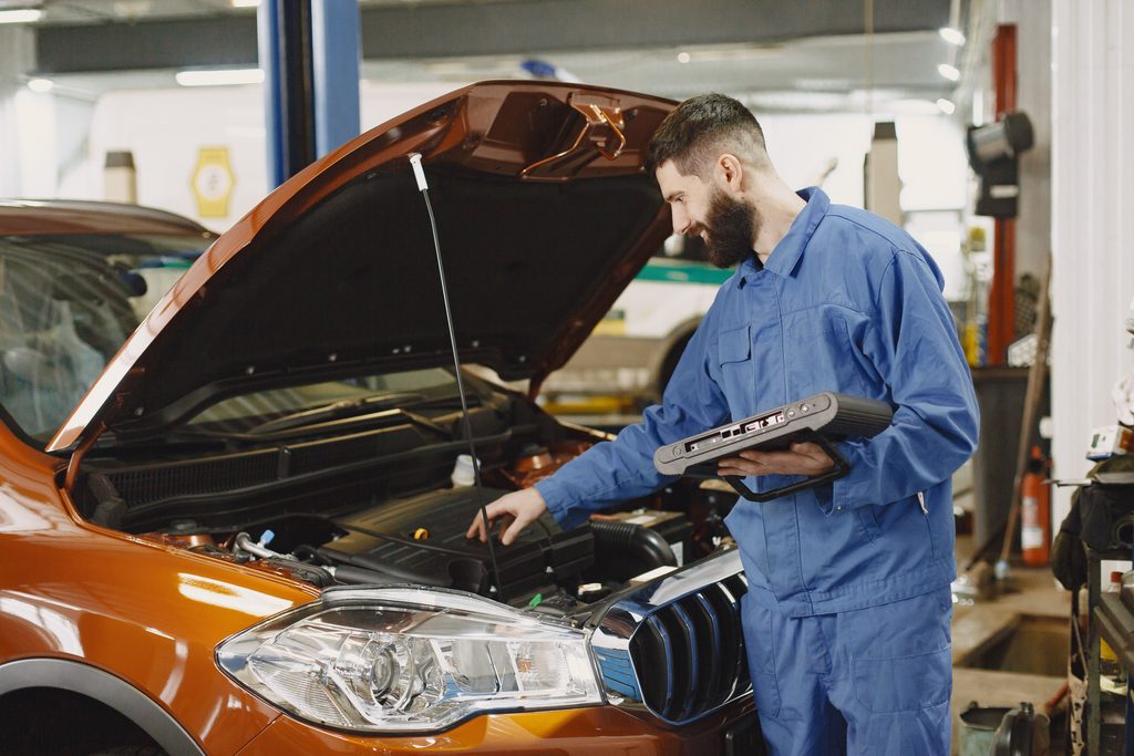 Skilled mechanic working on car engine diagnostics